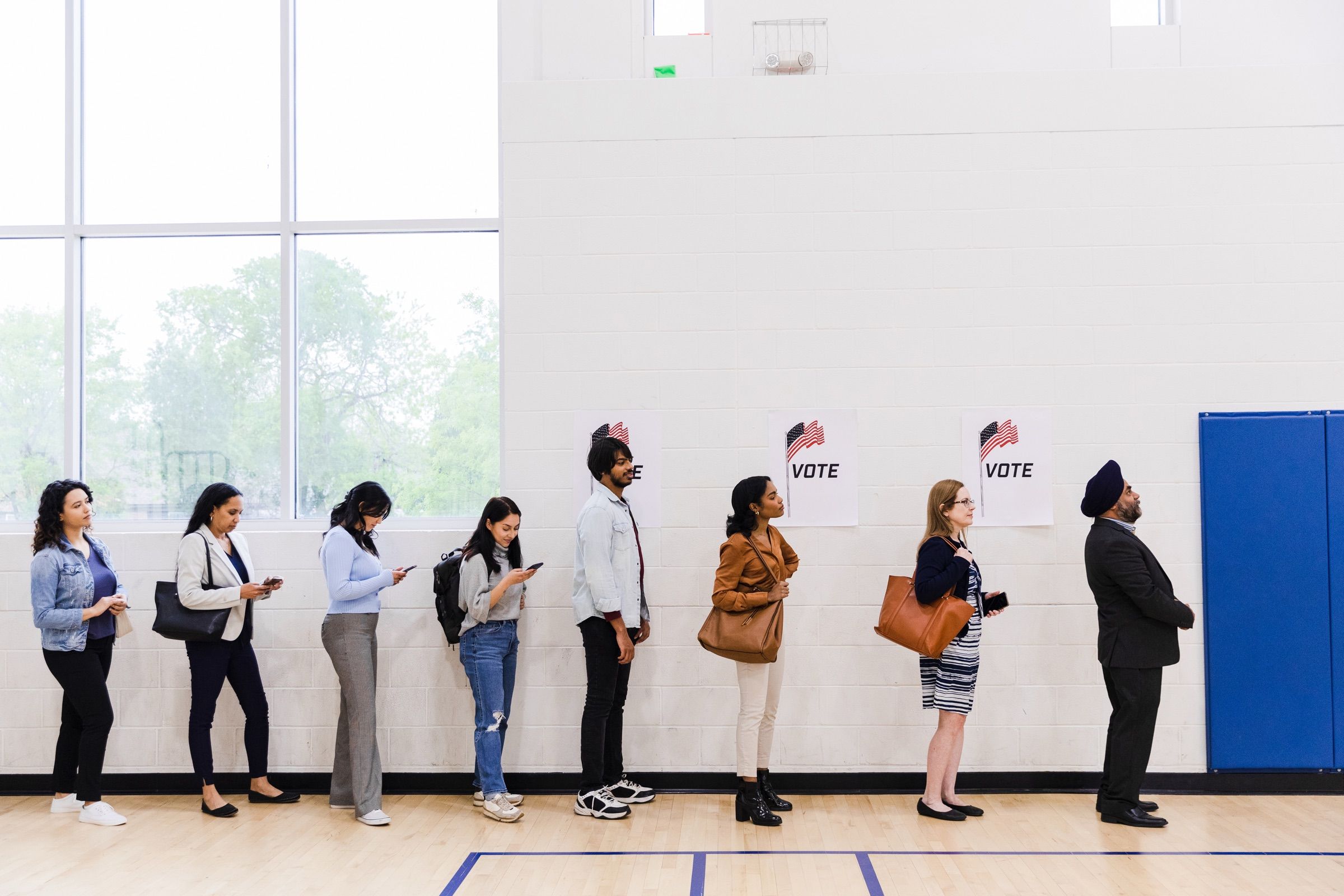 A line of voters waits inside a gym set up as a voting location.